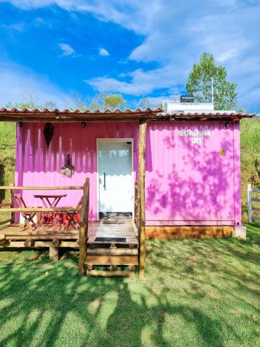 a pink shack with a wooden porch and a door at Pousada Recanto dos Bentos in Itapeva