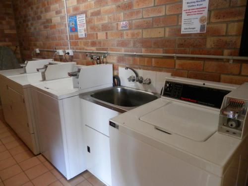a kitchen with a sink and a washing machine at Allan Cunningham Motel in Toowoomba