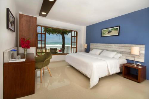 Un dormitorio con una gran cama blanca y una ventana en Casita de la Playa, en Puerto Villamil