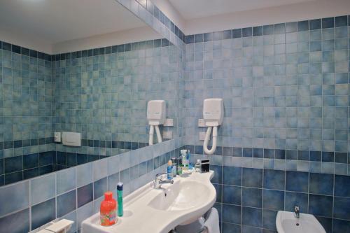 a blue tiled bathroom with a sink and a mirror at Hotel Il Viandante in Terranuova Bracciolini