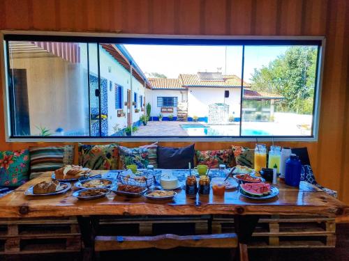 a wooden table with food on it with a large window at Pousada Recanto dos Bentos in Itapeva