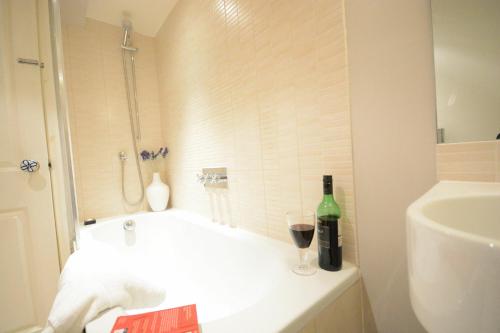 a bathroom with a tub with a glass of wine at 6 Coastguard Cottages, Aldeburgh in Aldeburgh