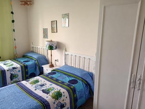 a bedroom with two beds with blue comforters at CASA ABUELA in Palacios de la Valduerna