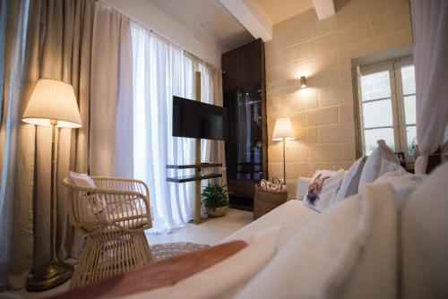 a hotel room with a bed and a chair and a television at Casa Maria Tereza in Cospicua