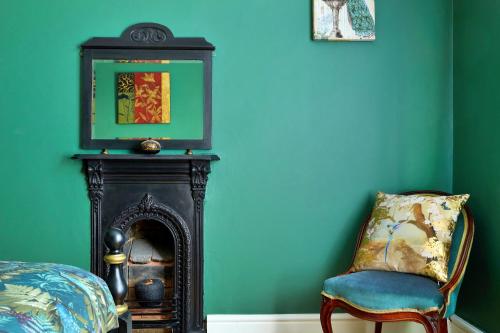 a chair and a mirror in a room with green walls at Finest Retreats - Peak View in Two Dales