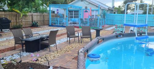 a backyard with a swimming pool and chairs and a house at Lake Worth Beach Paradise Cove Cottage 2-1Bedroom in Lake Worth
