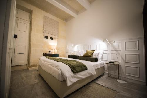 a bedroom with a large bed and a white wall at Casa Maria Tereza in Cospicua