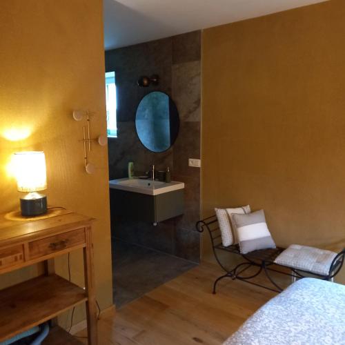 a bedroom with a bathroom with a sink and a chair at Le verger d' Adèle in Vielsalm
