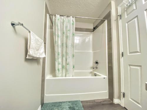 a white bath tub in a bathroom with a shower curtain at Cozy Newly Built and Cheerful 1-Bedroom Suite in Calgary