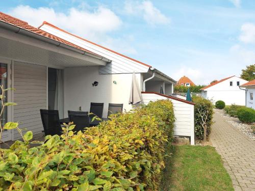 a house with chairs and a hedge in front of it at 4 person holiday home in r sk bing in Ærøskøbing