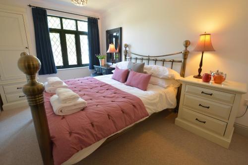 1 dormitorio con cama con sábanas rosas y escritorio en Badminton, Thorpeness, en Thorpeness