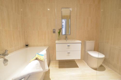 a bathroom with a tub and a toilet and a sink at Badminton, Thorpeness in Thorpeness