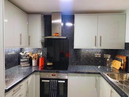 a kitchen with white cabinets and a black counter top at No.2 Folkestone in Folkestone