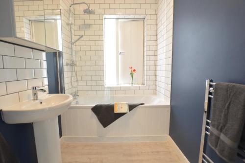 a bathroom with a sink and a bath tub with a window at Sweet Pea, Southwold in Southwold
