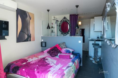 une chambre avec un lit rose et une cuisine dans l'établissement Studio Glamour Naturiste, au Cap d'Agde