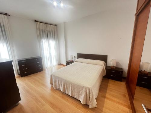 1 dormitorio con 1 cama y suelo de madera en Apartamentos Redondela - Centro histórico, en Redondela
