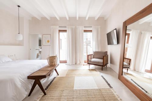 a white bedroom with a large bed and a chair at Meem Townhouse in Sóller