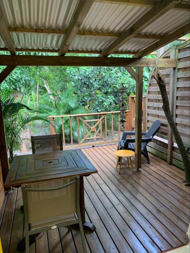 a wooden deck with a table and chairs on it at Les Manguiers in Deshaies