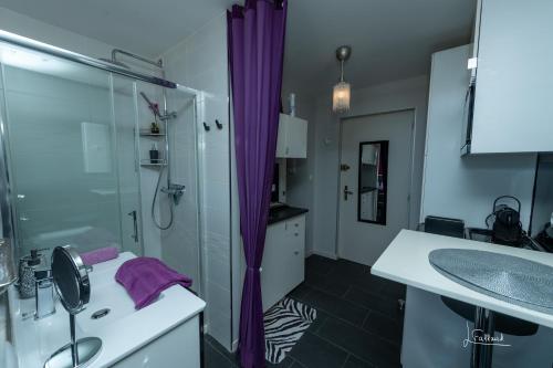 y baño con lavabo y ducha con cortinas moradas. en Studio Glamour Naturiste, en Cap d'Agde