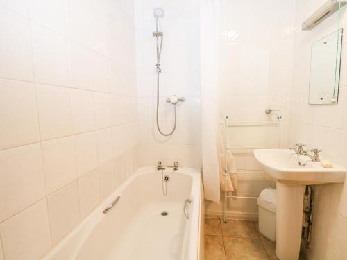 a white bathroom with a tub and a sink at Byre Cottage 3 in Pulborough