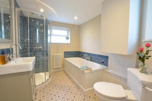 a bathroom with a tub and a toilet and a sink at Somewhere Only We Know, Aldeburgh in Aldeburgh