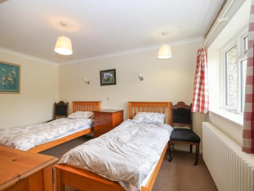 1 Schlafzimmer mit 2 Betten, einem Schreibtisch und einem Fenster in der Unterkunft Byre Cottage 4 in Pulborough