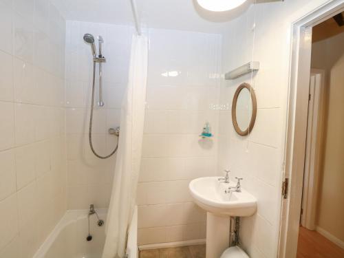 a white bathroom with a sink and a shower at Byre Cottage 2 in Pulborough