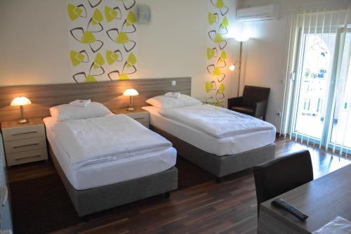 a hotel room with two beds and a desk at Vila DeLux in Negotin