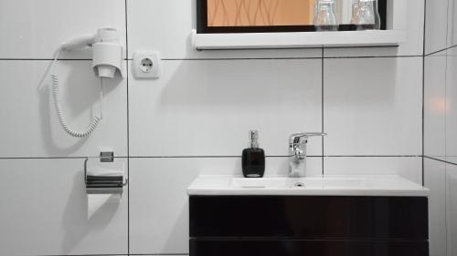 a white bathroom with a sink and a phone at Vila DeLux in Negotin