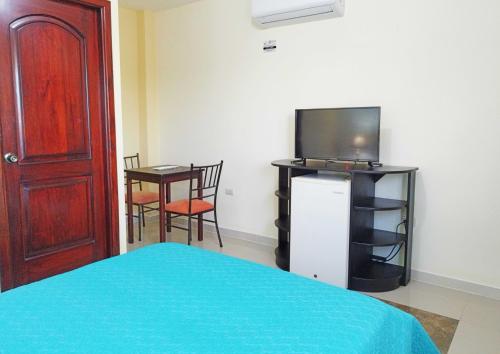 a bedroom with a bed and a tv and a table at Ocean Dreams Galapagos in Puerto Ayora