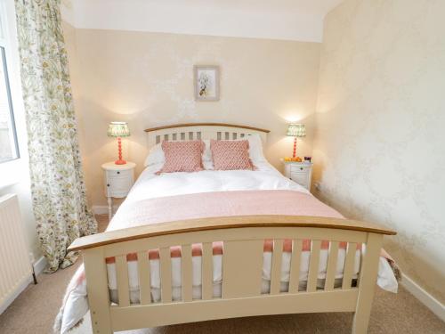 a white crib in a bedroom with two lamps at Dolphin Court in Colwyn Bay