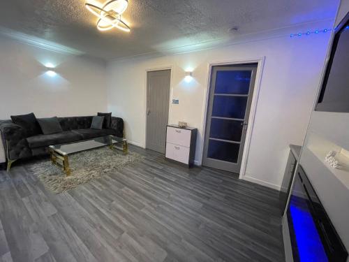 a living room with a black couch and a table at Newly refurbished modern 2 bedroom flat in Trimley Heath