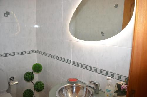 a bathroom with a sink and a round mirror at ESPAÇO ALVIM in Esmoriz