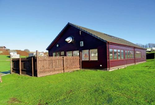 a black house with a wooden fence in a field at The Hidden Gem in Galloway Forrest in Balminnoch