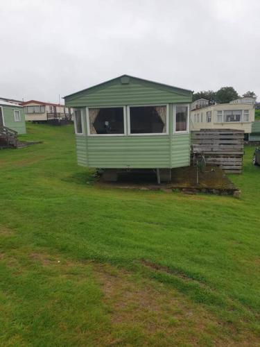 a green mobile home in a field of grass at The Hidden Gem in Galloway Forrest in Balminnoch
