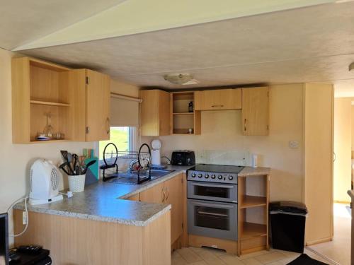 a kitchen with wooden cabinets and a stove top oven at The Hidden Gem in Galloway Forrest in Balminnoch
