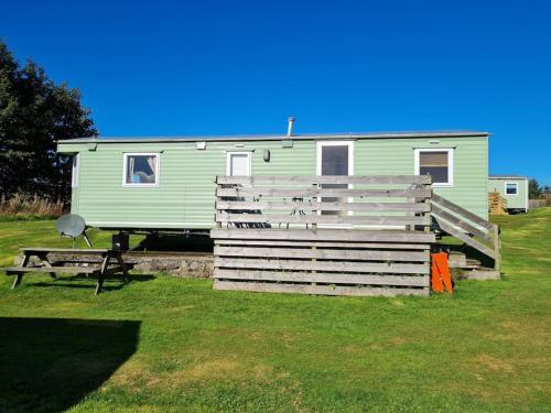 a green trailer with a picnic table and a bench at The Hidden Gem in Galloway Forrest in Balminnoch