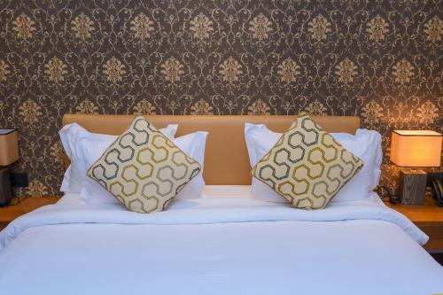 Una cama blanca con dos almohadas encima. en AQUA INN Hotel en Kinshasa