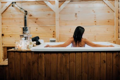 a woman is sitting in a bath tub at Świerkowisko cisza las plaża blisko in Ostróda