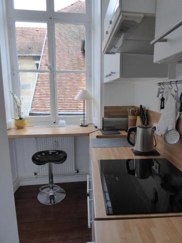 une cuisine avec un tabouret au milieu d'un comptoir dans l'établissement L'Annexe Apparthôtel du 11 C, 3 étoiles, studio, à Besançon