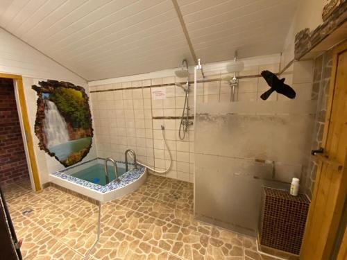 een badkamer met een bad en een douche bij "Ruhige Naturlage im Wald" Ferienhaus mit Sauna in Großnaundorf