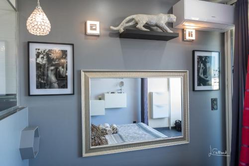 - un miroir mural dans une chambre avec des photos dans l'établissement Studio DIAMANT naturiste, au Cap d'Agde