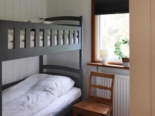 a bedroom with bunk beds and a chair and a window at Holiday home MUNKA-LJUNGBY III in Munka-Ljungby