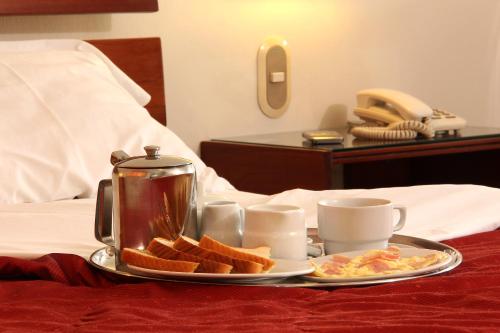 a breakfast tray with toast and coffee on a bed at Los Mirtos suite & Hotel in Lima