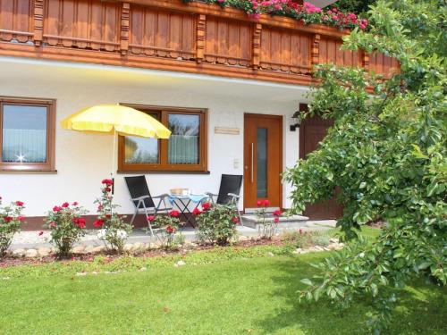 een huis met een tafel en stoelen en een paraplu bij Apartment in the valley of the Black Forest in Bernau im Schwarzwald