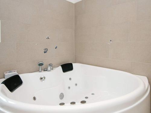 uma banheira branca numa casa de banho com azulejos em 12 person holiday home in R m em Rømø Kirkeby