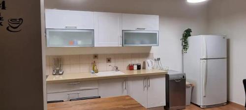 a kitchen with white cabinets and a white refrigerator at funattlv in Tel Aviv