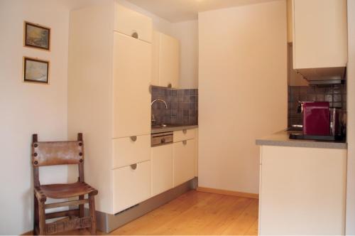 a kitchen with white cabinets and a chair in it at Appartement Ilse in Sankt Anton am Arlberg