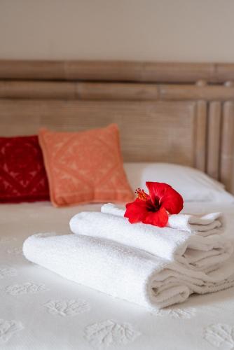 a towel on a bed with a red flower on it at Baja Azzurra in Bari Sardo