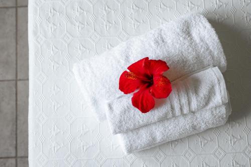 a white towel with a red flower on a bed at Baja Azzurra in Bari Sardo